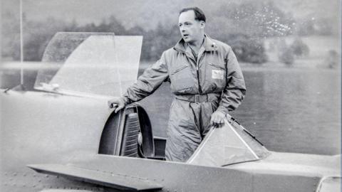 Donald Campbell standing in his boat Bluebird