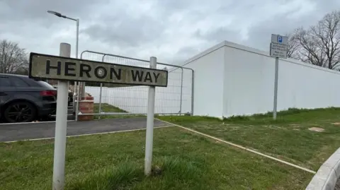 A view of a street sign with white construction fencing in the background.