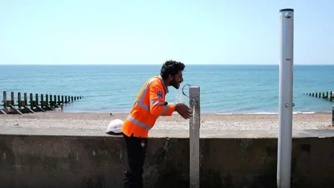 A man tries to keep cool by pouring water on his head. 