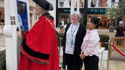 The Mayor sands in front of the new health kiosk in the shopping centre in Camberlet