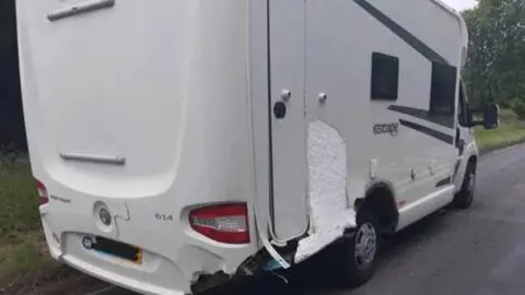 A white motorhome with damage to the back of the vehicle. 
