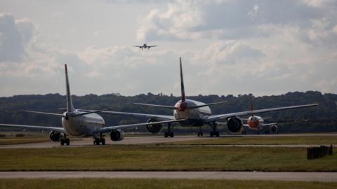 Passenger aircraft queue to take off from London Gatwick airport in Crawley, West Sussex