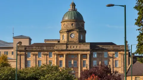 Dr Gray's Hospital in Elgin, a historic domed building pictured at sunset against a blue sky.