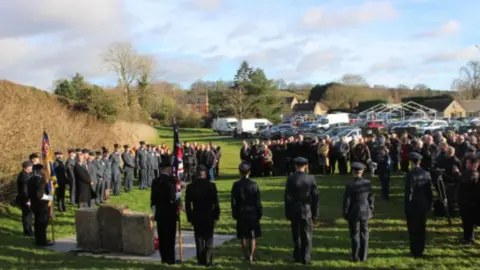 South Kesteven District Council A large group of people, including military personnel holding flags, standing around the newly unveiled memorial in Carlton Scroop. 