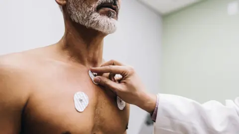 Getty Images Doctor performs electrocardiogram by placing electrode sensors on patient's chest