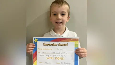 Supplied A boy holds up a certificate that reads "Superstar Award"