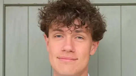 A head-and-shoulders shot of a man with brown curly hair smiling at the camera.