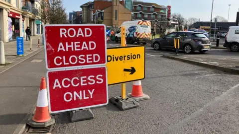 Red street sign saying road closed ahead and access only