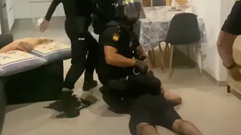 A police officer kneeling on the back of a suspect as they are arrested