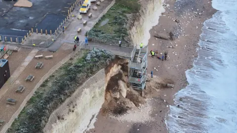 Eddie Mitchell A collasped white cliff on a sandy beach.