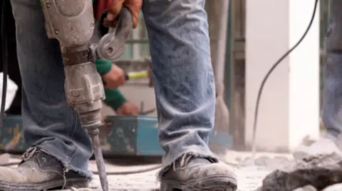 Getty Images A generic shot of a builders' feet with a jackhammer drill 