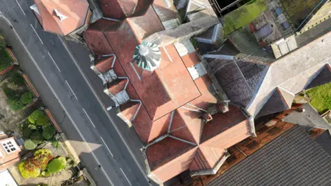 YouTube Andy Savage @Comedyhunter A birdseye view of the Derby School of Art. It has a red brick roof with many different sections.