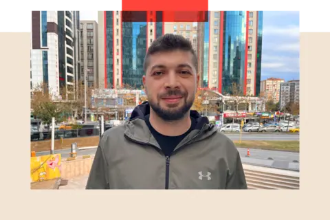 Photo of Hussam - a young big  antheral   with a moustache and trimmed beard. He is staring consecutive  to camera. Behind him is simply a roadworthy  and immoderate   precocious   emergence  buildings.