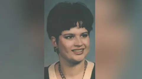 Suffolk Police A portrait shot of Karen Hales, who has dark hair and earrings and is wearing a necklace and a black top with a white top underneath. 