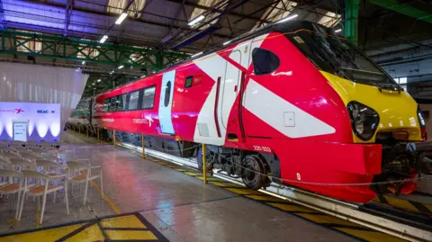 CrossCountry An image of a refurbished CrossCountry Voyager train inside a warehouse at a launch event. The train is mainly red, with a white X, which is partially on the driver's door.