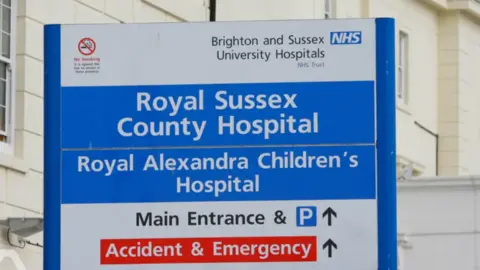 PA Media Uma placa fora do Royal Sussex County Hospital, com instruções para a entrada principal e o departamento de A&E.