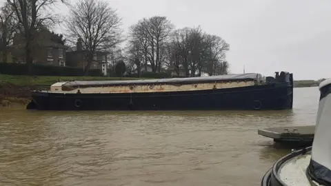 The barge, pictured in the middle of the river. 