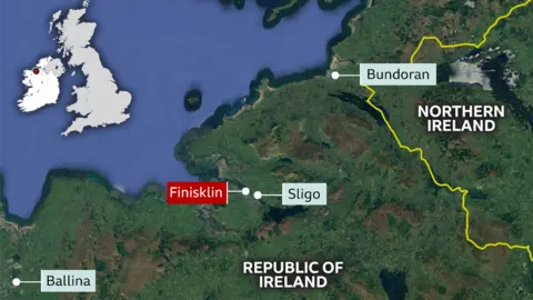 Google A graphic of a map shows dark green representing land and dark blue representing water. There are three locations indicated in light blue on the map and one in red. The one in red reads Finisklin. The rest read, from north to south, Bundoran, Sligo and Ballina. The blue sea area is on the north-west on the map, where a small graphic of the UK is visible. 