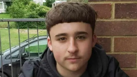 Head and shoulders photo of Owen Dunn wearing a black jacket and short brown hair