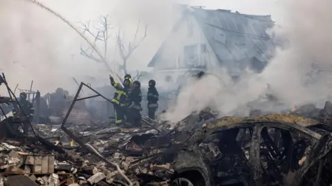 Reuters Emergency workers extinguish fires in the debris of a private house that was destroyed in a Russian rocket strike, amid Russia's attack on Ukraine, in Markhalivka, Kyiv region, Ukraine on 25 May 2025.