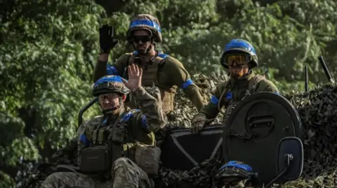 Reuters Three Ukrainian soldiers sit on top of a tank in the Sumy region