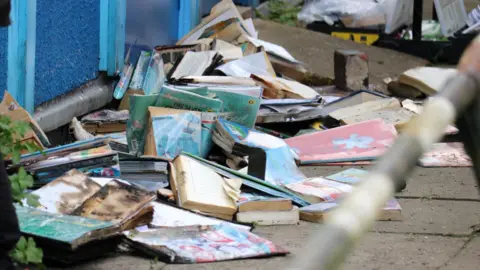 Stuart Woodward/BBC Burnt books piled up on the floor