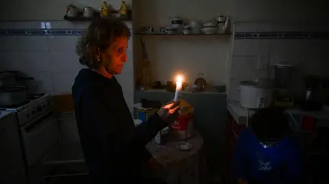 Getty Images A woman holds a candle during a blackout in Havana in January