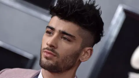 Zayn Malik attending the 60th Annual GRAMMY Awards at Madison Square Garden - he has his hair spiked up with a nose ring, and has a neutral expression on his face. 