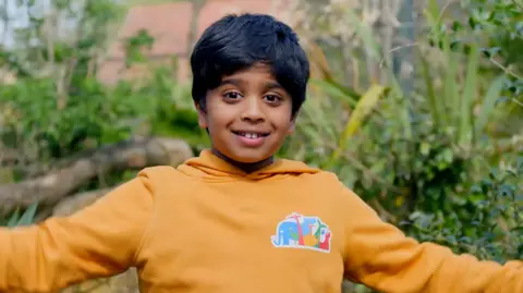 Aneeshwar Kunchala smiles for the camera in a yellow hoodie with an animal logo