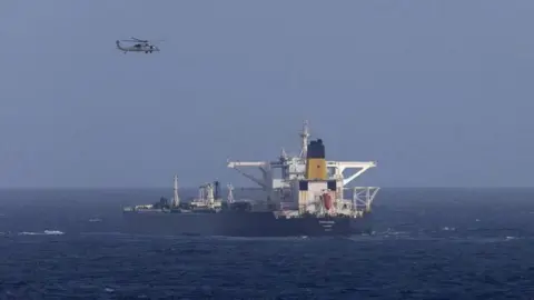 Reuters A helicopter flies over a ship in blue waters 