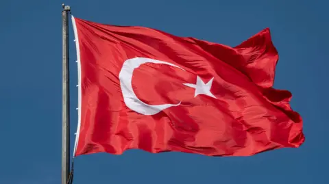 Getty Images The Turkish flag flying against a blue sky