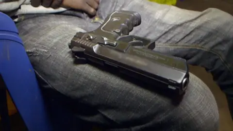 BBC A handgun sitting on someone's knee