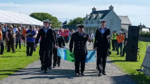 Muckle Media The Orkney Sea Cadets walking with a flag