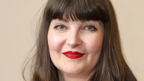 Dumfries and Galloway Council A woman with long dark hair and bright red lipstick looks directly into the camera