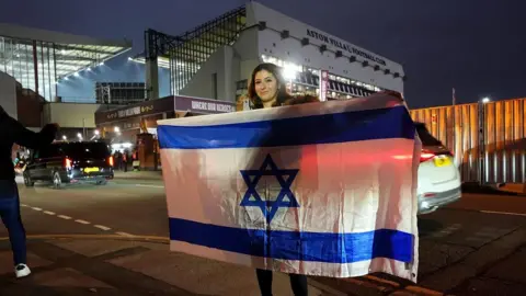 PA Media A fan carries an Israel flag near the ground before the UEFA Europa League match at Villa Park, Birmingham.