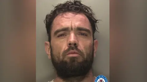 WMP A man, Mohammed Durnion, appears in a police mugshot. He has a dark beard and curly hair.