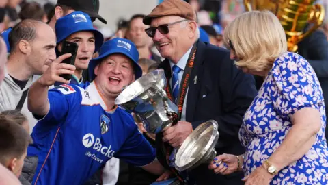 PA Media Oldham Athletic owner Frank Rothwell with the trophy during the Vanarama National League promotion celebrations at Boundary Park
