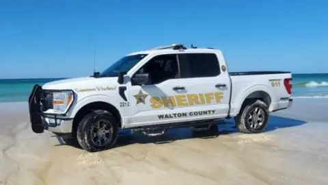 Walton Co Sheriff A picture of a sheriff's car parked on the sand