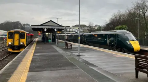 A wide shot of two green Great Western Railway trains at platforms at Par station.