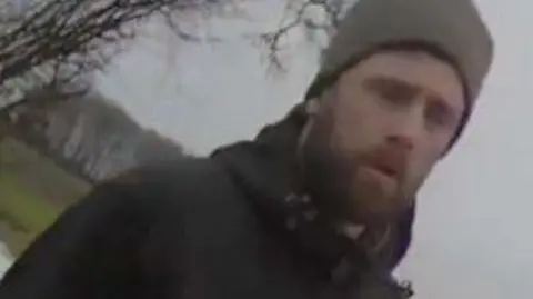 James Kent has a ginger beard and is wearing a grey beanie hat with a dark blue coat.