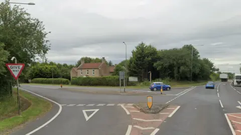 The A1079 junction with Cliffe Road. Cars can be seen on the road and the sky is overcast.