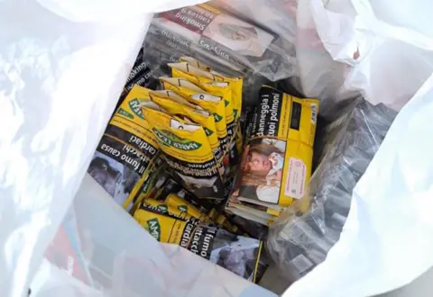 West Mercia Police A white plastic bag containing dozens of small yellow packets 