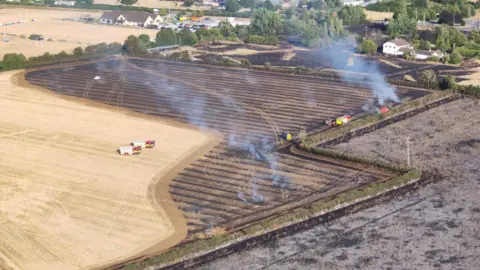 Wiltshire Search and Rescue A small fire engine move towards a burned field in an aerial photo. Two more are heading towards the field.