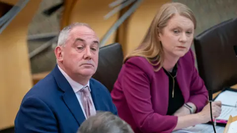 PA Media Housing Minister Paul McLennan sits beside Social Justice Minister Shirley-Anne Somerville during the debate in the Holyrood chamber