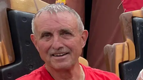 North Yorkshire Police An older man with short grey hair, wearing a red t-shirt, looks into the camera and smiles.