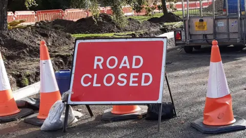 A road closed sign in red and white