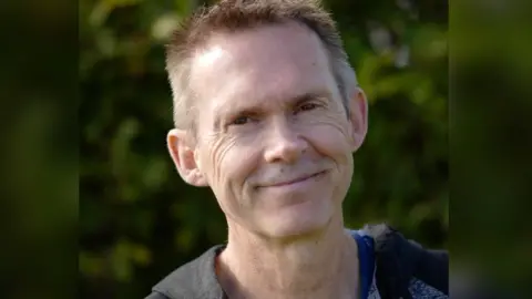 Miles Bingham A man with brown hair smiles at the camera.