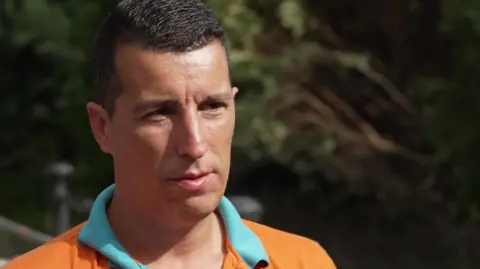 Bruno Aguiar wearing a orange t-shirt, he has short brown hair and is facing the camera