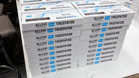 MHRA Many boxes of illegal Alluvi Trizepatide drugs all piled on a table. 