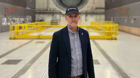 Head of test facilities Pat Hilton at Testbed 80 in Derby stood in a large testing warehouse.